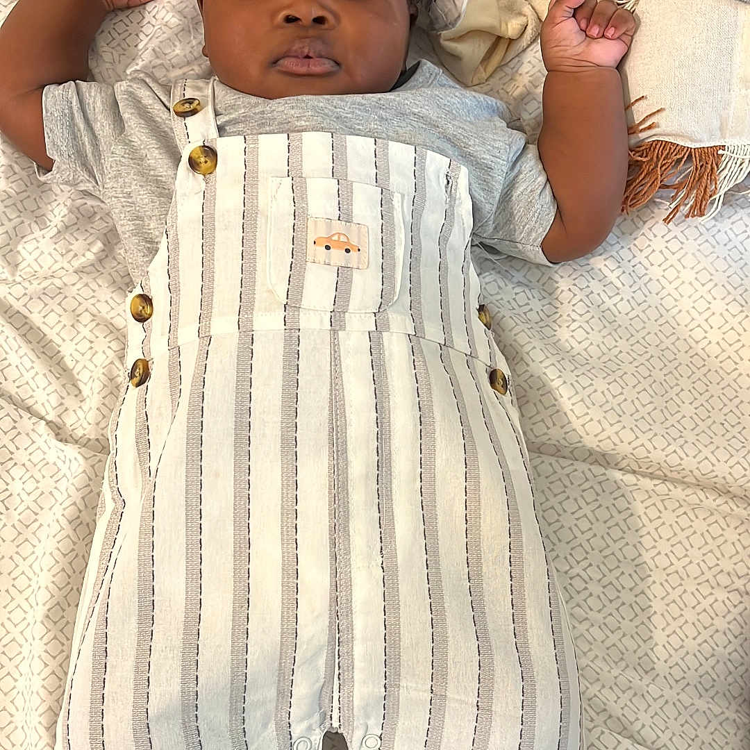 Ozar joined the competition — help win amazing prizes! baby, child, infant, portrait, lying_down, bed, bedding, blanket, patterned_background, striped_clothing, overalls, cap, hat, shoes, socks, fashion, adorable, looking_at_camera, indoor, smiling