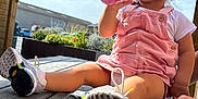 Harmonie participe au concours pour gagner de l'argent avec cette photo : child, toddler, pink_overalls, sitting, outdoor, sunlight, sky, wooden_deck, drinking, bottle, shoes, white_tshirt, pergola, plants, flowers, hand, curious, daylight, casual, young_child