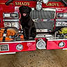 Dalton joined the competition — help win amazing prizes! dog, black_dog, fire_truck, vehicle, red, hose, headlight, metal, garage, animal, pet, smiling, sitting, equipment, reflection, floor, emergency_vehicle, machinery, front_bumper, industrial
