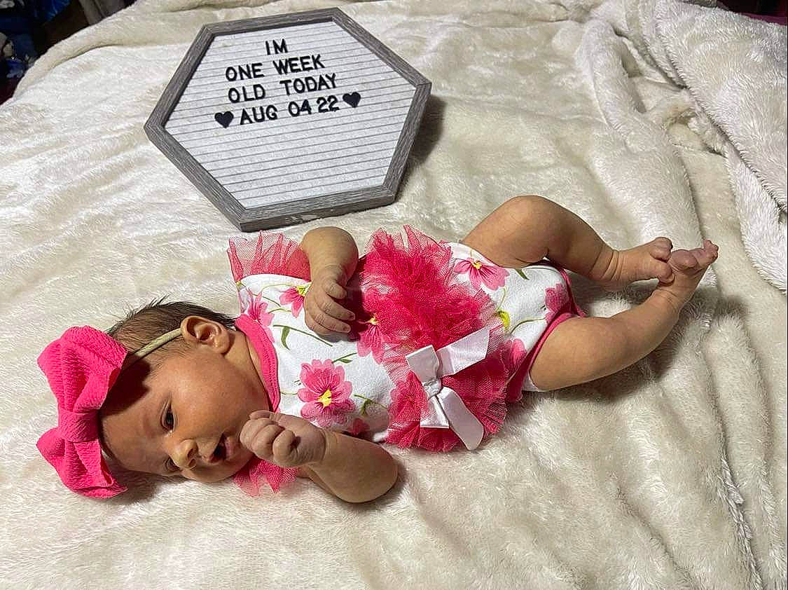 Jaslynn joined the competition — help win amazing prizes! baby, baby_toddler_clothing, bed, bedding, child, comfort, eye, finger, foot, happy, headwear, human_body, human_leg, linens, mammal, person, pink, product, skin, textile