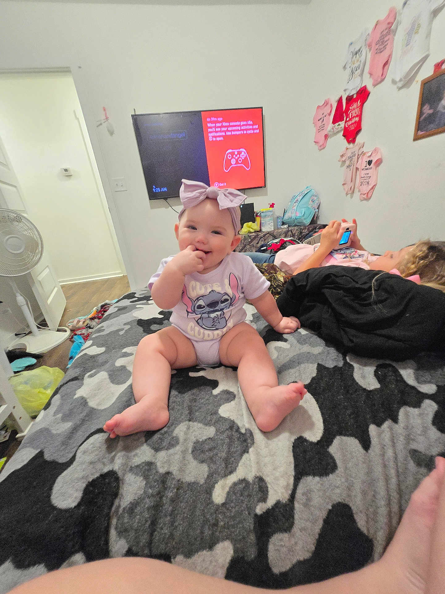 Amelia Stanberry joined the competition — help win amazing prizes! baby, child, bow, bed, blanket, camouflage, clothing, device, furniture, game_console, headband, indoor, person, playing, room, screen, smiling, technology, toddler, wall