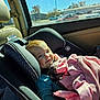 baby, car_seat, blanket, child, car_interior, sunlight, window, seat, child_seat, infant, clothing, pink, blue, happy, smile, person, face, head, daytime, vehicle