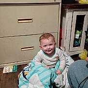 Amelia Stanberry is registered to the contest to win money with this photo: baby, child, smiling, blanket, pajamas, dresser, cabinet, cat, pet, wood_floor, book, toiletry_bottle, diaper_pack, toddler, indoor, cozy, happy, portrait, furniture, playtime