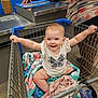 baby, shopping_cart, blanket, smiling, child, indoor, person, retail, store, clothing, happy, seat, toddler, holding, arm, cute, face, retail_store, floor, adult