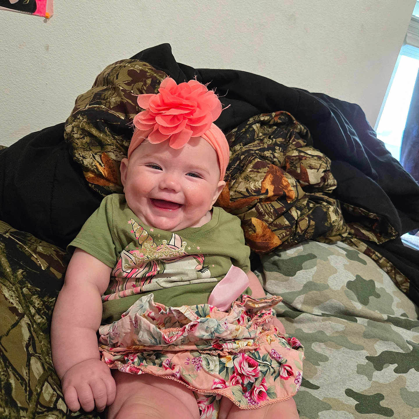 Amelia is registered to the contest to win money with this photo: baby, blanket, camouflage, child, clothing, couch, cozy, cute, fabric, flower, happy, headband, home, indoors, infant, person, portrait, sitting, skirt, smiling