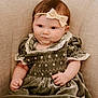baby, infant, child, headband, bow, green_dress, velvet, couch, beige, soft_fabric, cute, smirk, indoor, portrait, chubby_cheeks, sitting, neutral_colors, cozy, person, young_child
