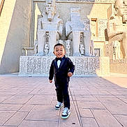 Patrick is registered to the contest to win money with this photo: ancient, architecture, boy, carved, child, culture, egyptian, hieroglyphics, historical, monument, outdoor, shadow, smiling, sneakers, statues, stone, sunlight, tourist, tuxedo, walking
