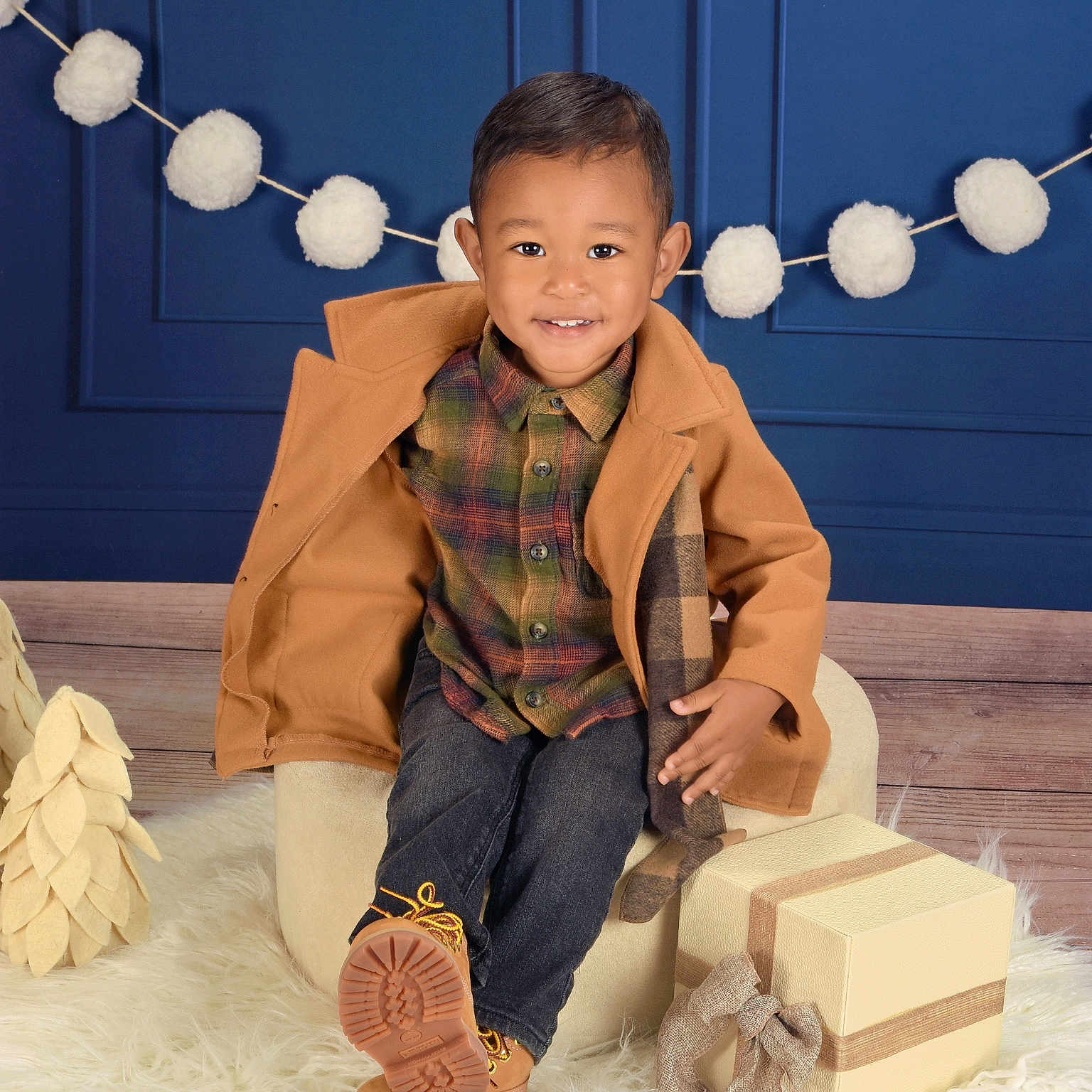 Patrick joined the competition — help win amazing prizes! child, smiling, plaid_shirt, tan_coat, jeans, boots, gift_box, chair, fluffy_rug, pom_pom_garland, blue_wall, holiday_decor, indoor, portrait, cute, happy, fashion, cozy, wood_floor, celebration