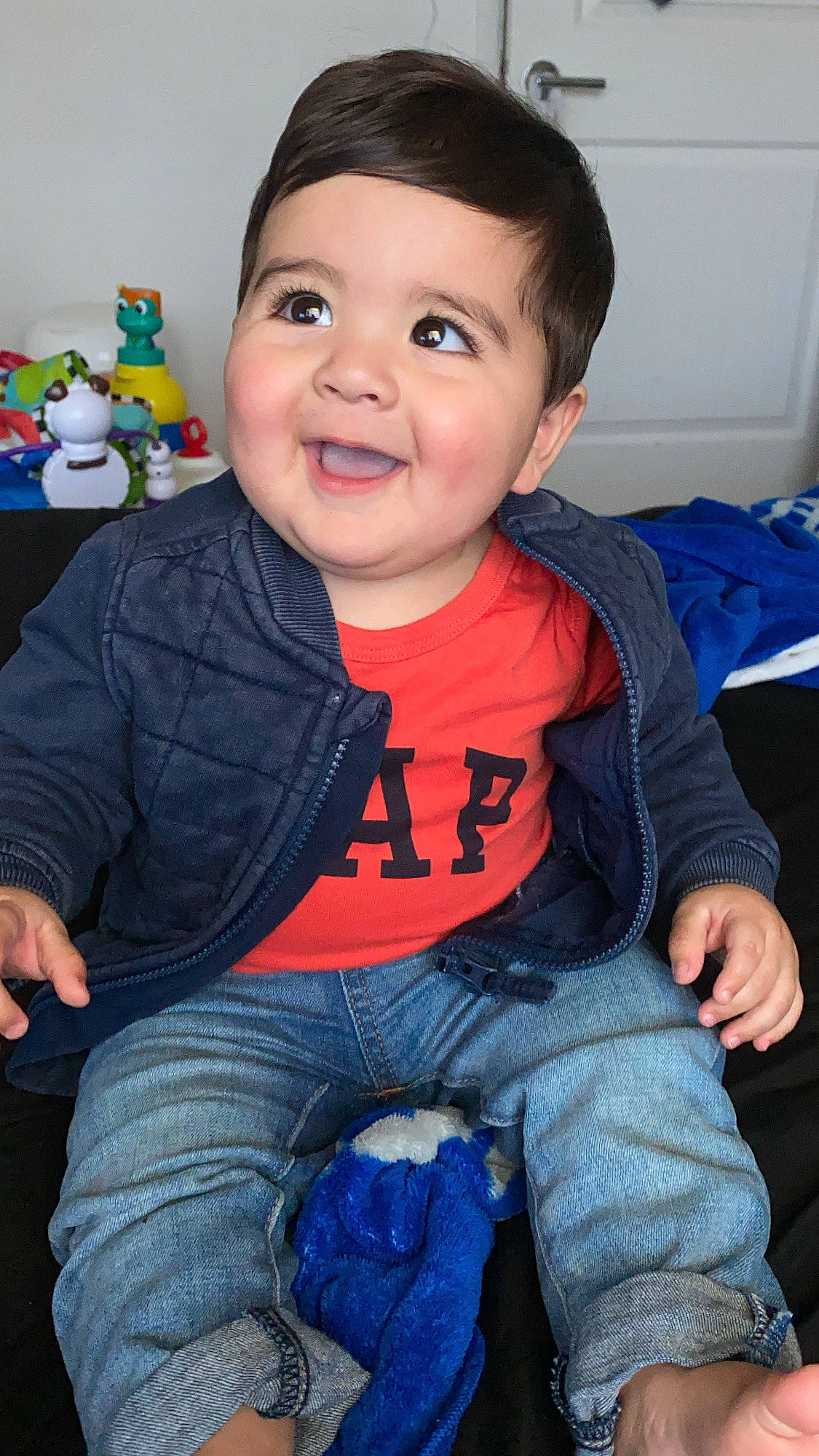 Jesus is registered to the contest to win money with this photo: arm, baby_toddler_clothing, blue, cheek, eye, face, facial_expression, finger, forehead, hairstyle, head, iris, jeans, joy, mouth, nose, organ, person, skin, sleeve