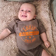 Louis a rejoint le concours — aidez-le/la à gagner de superbes lots ! baby, smiling, tongue_out, onesie, blanket, couch, infant, happy, cute, lying_down, face, head, skin, furniture, cozy, soft_texture, child, small_hands, small_feet, indoor