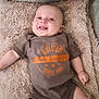 baby, smiling, tongue_out, onesie, blanket, couch, infant, happy, cute, lying_down, face, head, skin, furniture, cozy, soft_texture, child, small_hands, small_feet, indoor