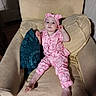 Remi is registered to the contest to win money with this photo: toddler, child, pajamas, pink, headband, armchair, beige, pillow, blue, patterned, indoor, wooden_floor, curious, smile, barefoot, relaxed, cushion, person, portrait, home