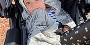 Romy a rejoint le concours — aidez-le/la à gagner de superbes lots ! baby, blanket, stroller, child, blue_eyes, hooded_blanket, outdoor, sunlight, person, infant, seat, comfort, soft_texture, nibble, black_stroller, patterned_handle, face, curious, wrapped, clothing