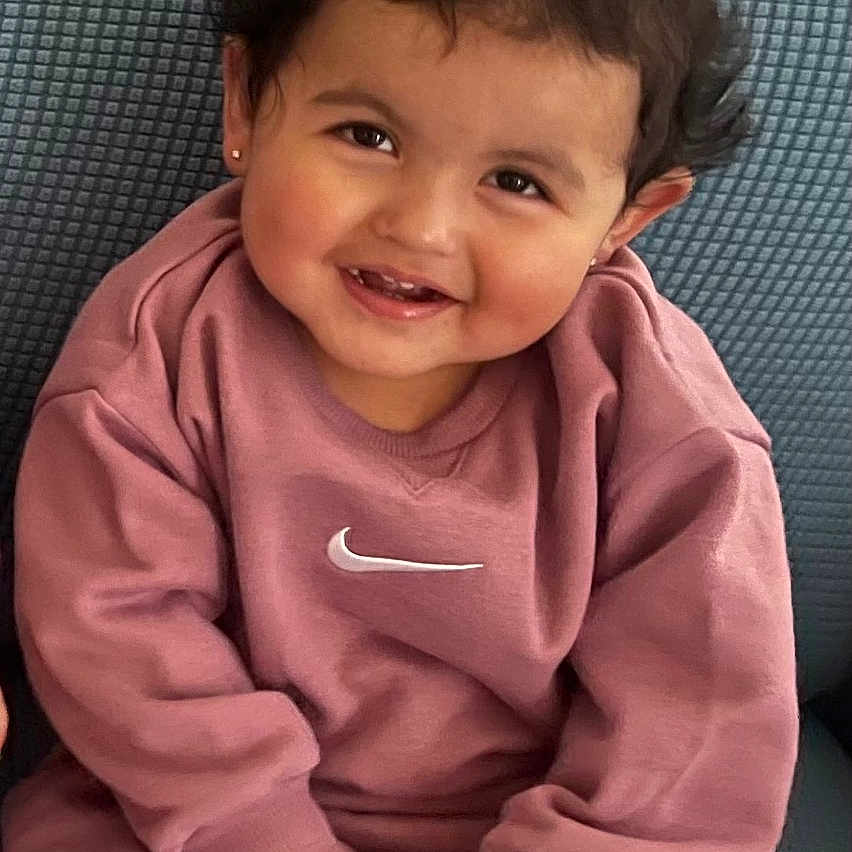 Maya is registered to the contest to win money with this photo: baby, babylaughing, bodypart, clothing, couch, cushion, face, furniture, happy, head, homedecor, laughing, mouth, pants, person, photography, portrait, sitting, smile, teeth