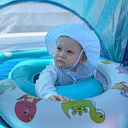 Caiden joined the competition — help win amazing prizes! baby, child, inflatable, pool, float, hat, white_clothing, blue, water, canopy, dinosaur, cartoon, hand, face, expression, outdoor, summer, swimming, toy, cute