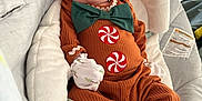 Finley is registered to the contest to win money with this photo: baby, infant, child, cute, costume, gingerbread, orange_outfit, green_bow_tie, peppermint_buttons, baby_seat, blanket, white_mittens, white_socks, soft_cushion, indoors, window_blinds, cozy, portrait, relaxed, holiday_theme