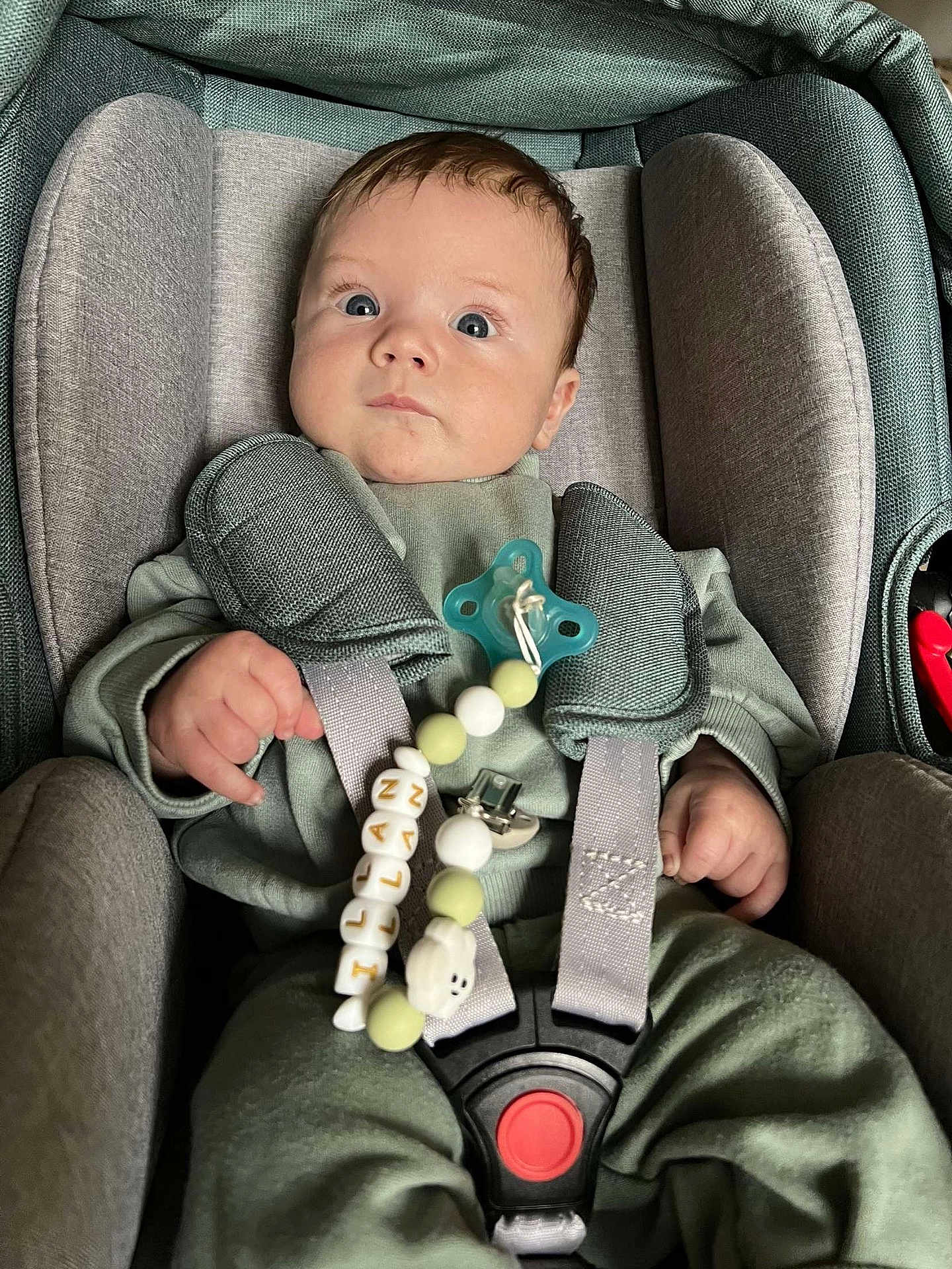 Illan a rejoint le concours — aidez-le/la à gagner de superbes lots ! baby, car_seat, pacifier, pacifier_clip, green_clothing, infant, child, straps, seat_belt, close_up, indoor, person, cute, face, hand, blue_eyes, soft_fabric, sitting, comfortable, young_child