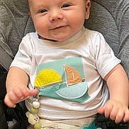 Illan participe au concours pour gagner de l'argent avec cette photo : baby, infant, child, smiling, white_shirt, diaper, pacifier, beads, name_tag, gray_seat, cushion, cute, happy, indoor, portrait, young_child, playful, clothing, person, seat