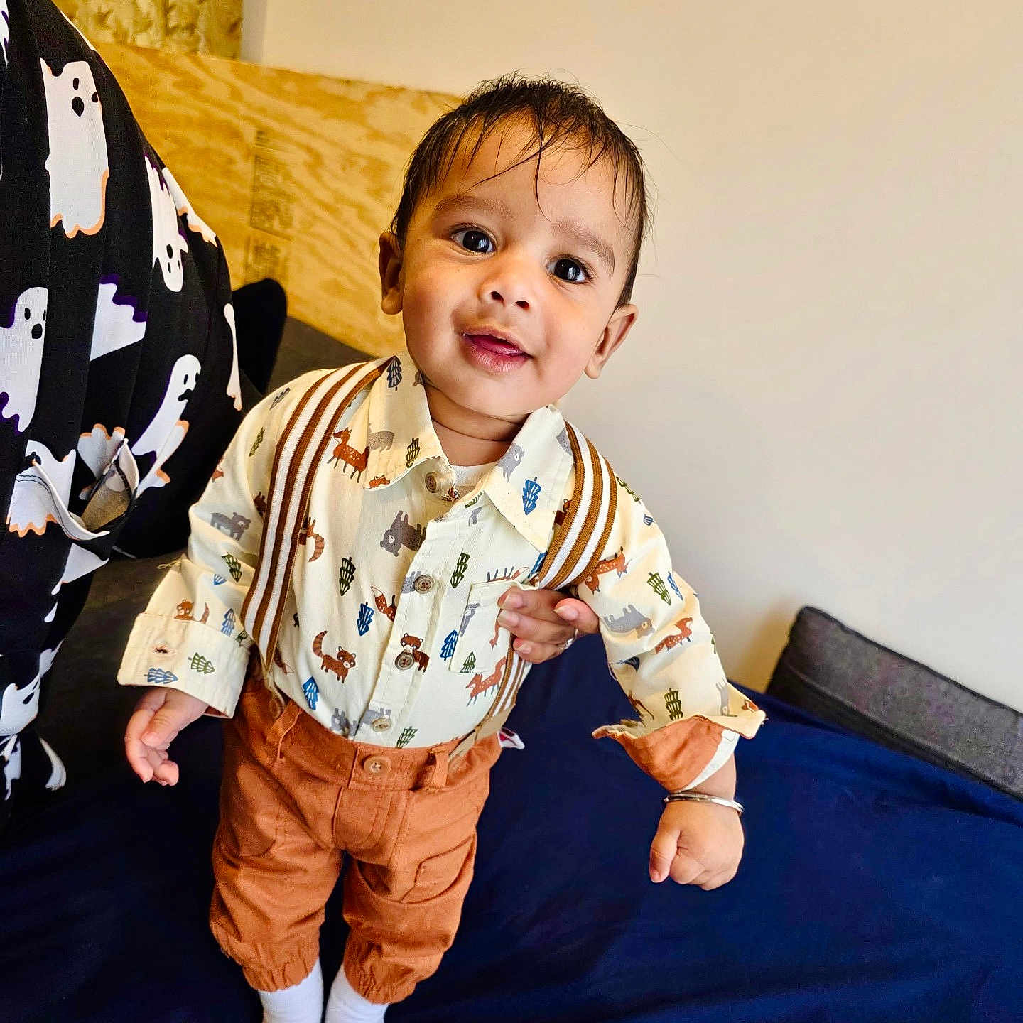 Gurnawab is registered to the contest to win money with this photo: toddler, child, smile, standing, shirt, pants, suspenders, bed, bedspread, person, ghost_pattern, indoor, happy, cute, portrait, clothing, face, hand, footwear, home