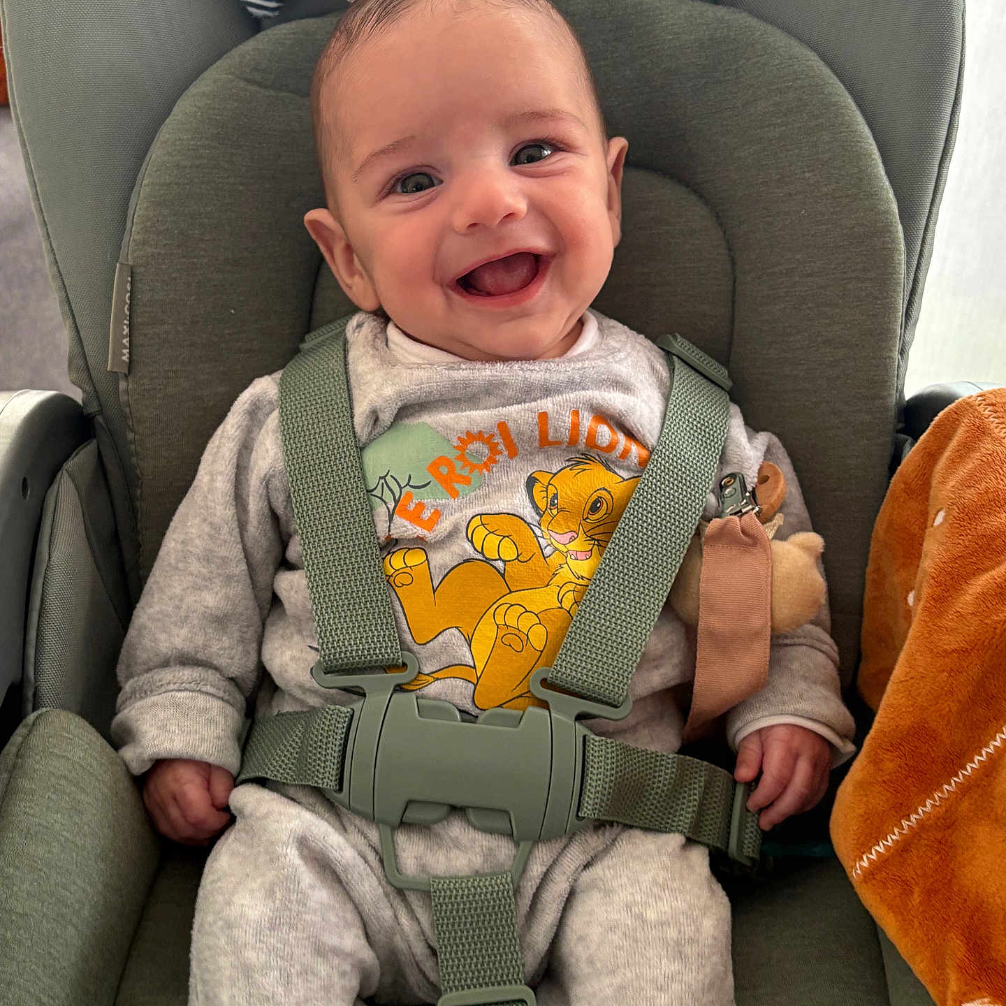 Nino participe au concours pour gagner de l'argent avec cette photo : accessories, baby, babylaughing, car, clothing, cushion, face, furniture, gun, happy, head, homedecor, pants, person, photography, portrait, strap, transportation, vehicle, weapon