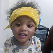 Timothy joined the competition — help win amazing prizes! child, toddler, curly_hair, yellow_bandana, pajamas, dinosaur_print, food_print, indoor, face, smiling, person, young_child, cute, casual_clothing, portrait, headwear, expression, home, furniture, drawer