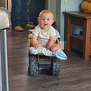 Andrew joined the competition — help win amazing prizes! baby, toy, dump_truck, blanket, indoor, child, floor, furniture, person, jeans, shoes, wooden_floor, table, blue_wall, happy, sitting, footwear, play, cute, home