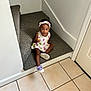 Pheobe joined the competition — help win amazing prizes! toddler, child, indoor, stairs, carpet, dress, headband, shoe, tile_floor, snack, sitting, curious, person, young_child, wall, door, footwear, headwear, brown_skin, casual_clothing