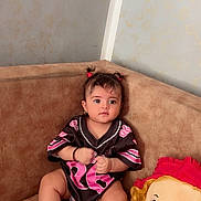 Céline participe au concours pour gagner de l'argent avec cette photo : baby, brown_furniture, casual_clothing, child, comfort, couch, curly_hair, cute, expression, home, indoor, infant, jersey, person, pigtails, playful, plush_doll, portrait, sitting, toy