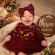 Rowyn joined the competition — help win amazing prizes! autumn, baby, blanket, bow, child, cute, floral, flower, happy, headband, indoors, infant, knit, maroon_dress, portrait, sign, sitting, smiling, three_months, wooden_sign
