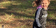 Alyia is registered to the contest to win money with this photo: child, girl, outdoor, sunlight, tracksuit, adidas, pink_crocs, grass, trailers, shadow, motion, happy, casual_clothing, playful, daylight, person, pigtails, nature, ground, footwear