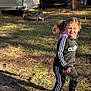 child, girl, outdoor, sunlight, tracksuit, adidas, pink_crocs, grass, trailers, shadow, motion, happy, casual_clothing, playful, daylight, person, pigtails, nature, ground, footwear