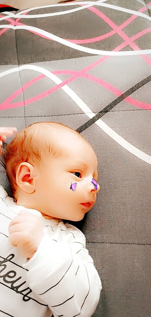Liam a rejoint le concours — aidez-le/la à gagner de superbes lots ! asphalt, baby, baby_toddler_clothing, cheek, child, doll, eyelash, fashion_accessory, flooring, grass, hairstyle, nose, pattern, person, pink, road_surface, skin, toddler, toy, white