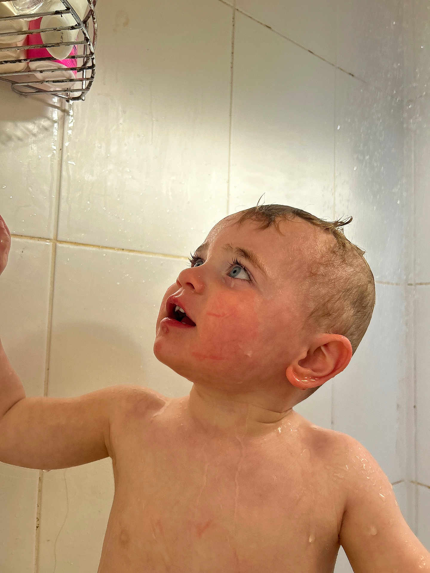 Mason joined the competition — help win amazing prizes! toddler, child, wet, bathroom, shower, water, skin, face, curious, blue_eyes, hair, soap_holder, tiles, bath_time, expression, head, shoulder, adult_hand, water_droplets, indoor