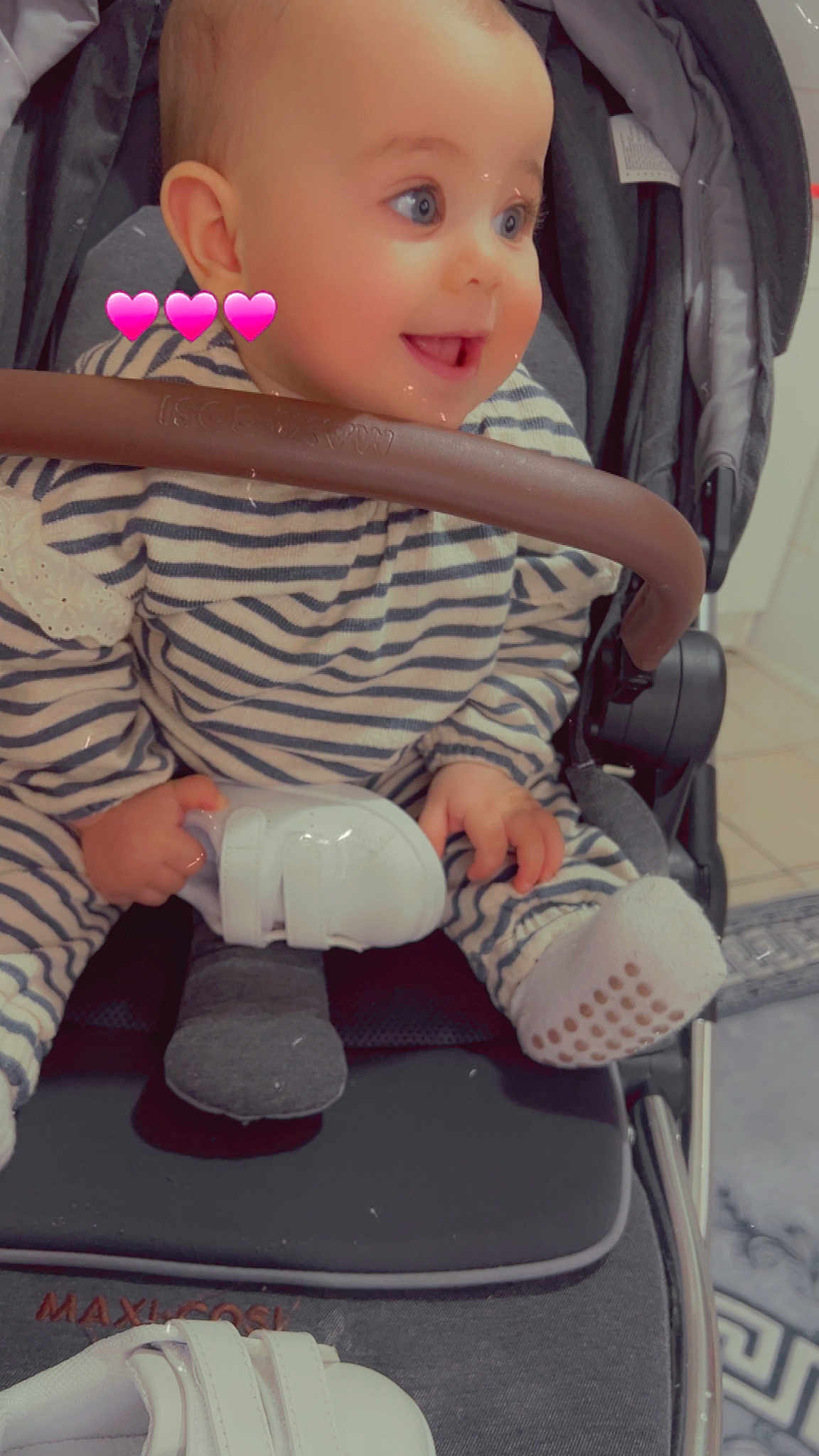 Line Anais a rejoint le concours — aidez-le/la à gagner de superbes lots ! baby, infant, child, stroller, striped_onesie, striped_clothing, smiling, blue_eyes, white_shoe, holding_shoe, socks, grip_bar, seat, hand, pink_hearts, carseat, cute, portrait, floor_tiles, soft_filter