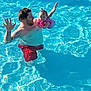 Chevy is registered to the contest to win money with this photo: child, man, swimming_pool, water, floatation_device, tattoos, summer, outdoor, fun, family, parent, baby, play, smile, waving, red_shorts, sunlight, happy, recreation, pool