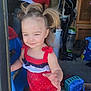 toddler, child, pigtails, red_romper, smiling, indoor, toy, blue, person, adult, garage, background, clutter, floor, hand, playful, hair, light, casual, expression