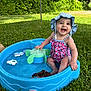 baby, child, smiling, swimsuit, hat, water, pool, toy, outdoor, grass, summer, play, happy, sitting, nature, sunlight, greenery, cute, fun, water_toy
