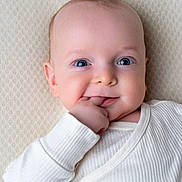 Meïr a rejoint le concours — aidez-le/la à gagner de superbes lots ! baby, blanket, blue_eyes, chubby_cheeks, close_up, cozy, cute, finger_in_mouth, gaze, hand, indoor, infant, lying_down, onesie, portrait, skin, smile, soft_lighting, textured_background, white_clothing