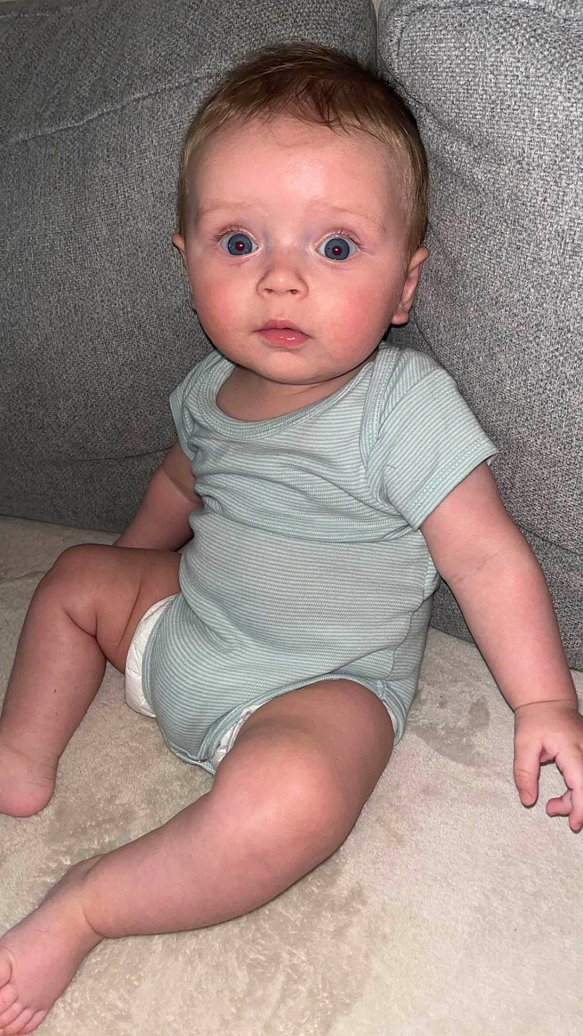 Kélyan participe au concours pour gagner de l'argent avec cette photo : baby, baby_toddler_clothing, barefoot, cheek, chest, child, chin, comfort, eye, finger, foot, human_leg, iris, leg, lip, person, sitting, skin, sleeve, surprise