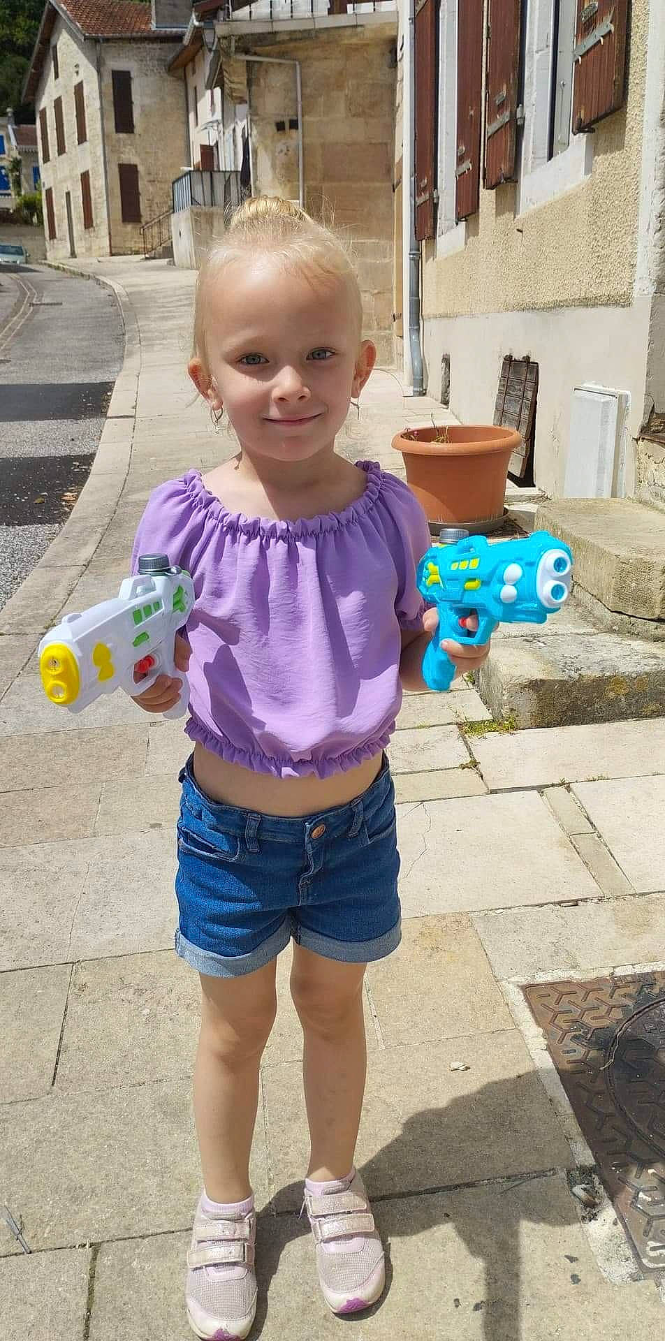 Emmy a rejoint le concours — aidez-le/la à gagner de superbes lots ! asphalt, child, denim, facial_expression, fun, hairstyle, happy, joint, joy, leisure, person, pink, shorts, sleeve, smile, standing, street_fashion, t_shirt, thigh, toddler