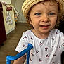 Amy a rejoint le concours — aidez-le/la à gagner de superbes lots ! blue_eyes, cherry_pattern, child, clothing, curious, curly_hair, cute, dress, face, handle, home, indoor, kitchen, person, smile, standing, straw_hat, toddler, toy, young_child