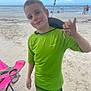 child, boy, beach, sand, ocean, sea, smile, green_shirt, hat, crab, chair, folding_chair, shorts, vacation, summer, shore, water, person, smiling, sunny