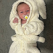 Denis joined the competition — help win amazing prizes! baby, infant, pacifier, white_robe, hood, bunny_ears, fluffy, soft_texture, carpet, lying_down, cute, cozy, newborn, child, small_hands, face, expression, indoor, comfortable, wearing_clothes