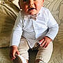 Nino a rejoint le concours — aidez-le/la à gagner de superbes lots ! baby, child, infant, boy, white_shirt, bow_tie, beige_pants, white_shoes, sitting, couch, patterned_couch, curious_expression, indoors, portrait, cute, young_child, hand, footwear, smiling, furniture