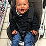 Nino participe au concours pour gagner de l'argent avec cette photo : baby, smiling, stroller, black_sweater, blue_jeans, happy, child, indoor, shopping_aisle, floor_tiles, seatbelt, cute, hands, jeans, clothing, person, retail, store, casual, portrait