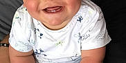 Nino a rejoint le concours — aidez-le/la à gagner de superbes lots ! baby, smiling, child, infant, happy, cute, person, face, cheeks, sitting, clothing, white_shirt, patterned_shirt, hand, lap, indoors, skin, head, eyes, mouth