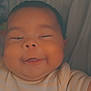 Liam is registered to the contest to win money with this photo: baby, smile, face, cheeks, onesie, striped_clothing, text_on_clothing, infant, lying_down, soft_lighting, closeup, cute, child, happy, skin, person, indoors, expression, head, sleepy