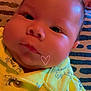 Liam is registered to the contest to win money with this photo: baby, child, face, infant, yellow_shirt, dinosaur_print, buttoned_shirt, chubby_cheeks, close_up, patterned_blanket, cute, portrait, indoors, laying_down, soft_lighting, pink_doodle, heart_doodle, crescent_moon, clothing, young_child