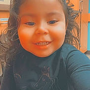 Novah joined the competition — help win amazing prizes! child, toddler, smiling, curly_hair, indoor, black_shirt, unicorn, face, person, long_sleeves, happy, young_child, cute, portrait, childhood, casual_clothing, human, expression, warm_lighting, background