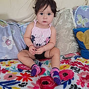 May joined the competition — help win amazing prizes! toddler, child, baby, sitting, couch, blanket, pillow, colorful, floral, clothing, socks, face, hair, indoor, cute, portrait, person, expression, home, cozy